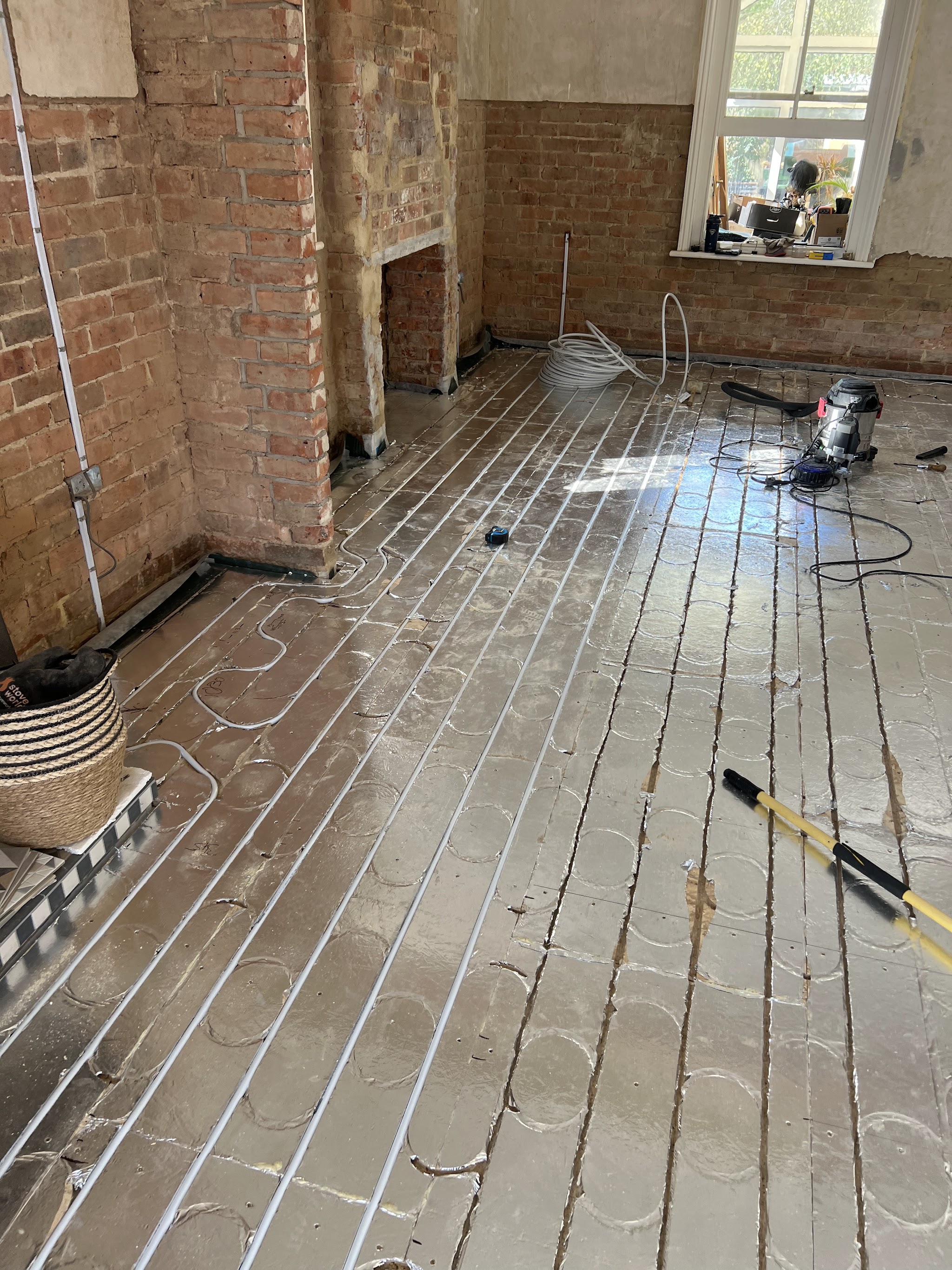 Underfloor heating pipework laid across a stripped-back room