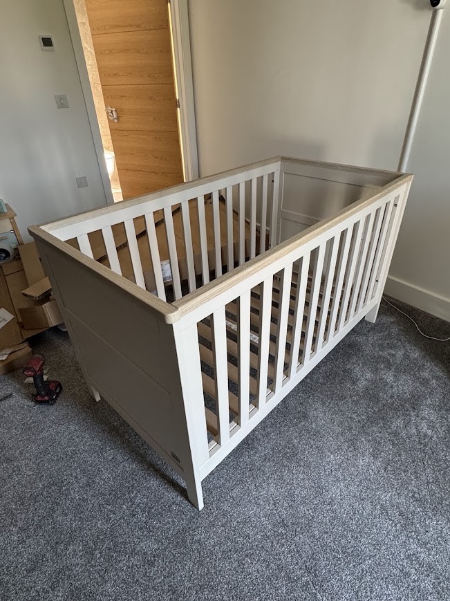 White and oak cot assembled in a nursery