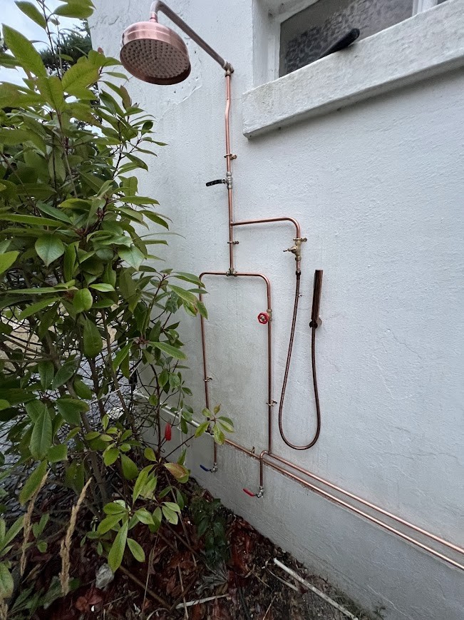 Copper outdoor shower pipework on an exterior wall
