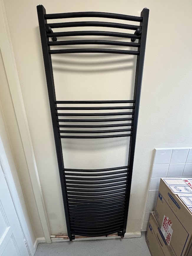 Black heated towel rail fitted in a bathroom